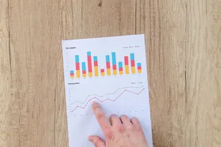 A hand pointing to a printed financial chart
